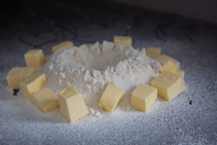 Slices of butter around flour prepared for kneading