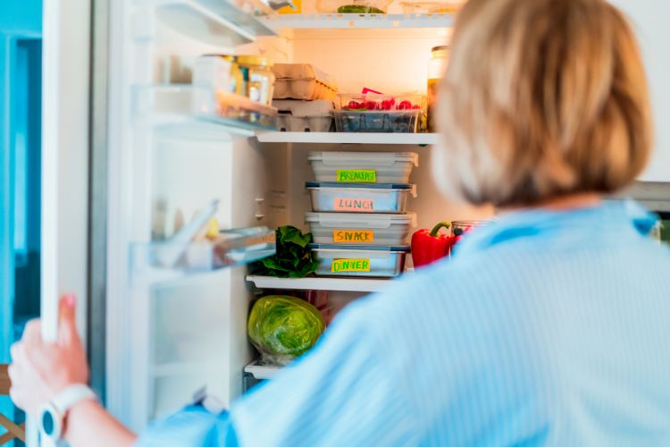 A woman putting something in the fridge