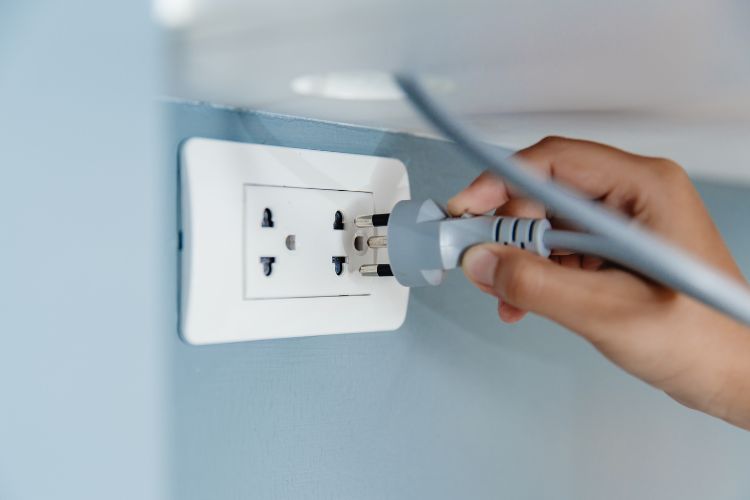 Closeup Hand Plug in Wall Socket