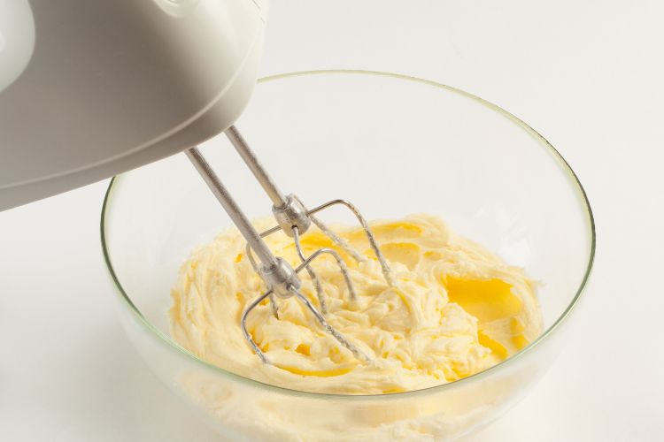Making buttercream in a bowl with an electric mixer