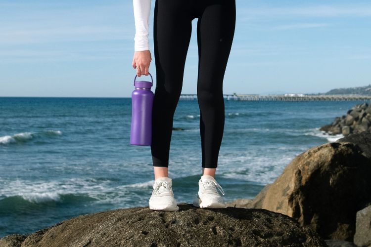 Woman at the beach holding her hydro flask