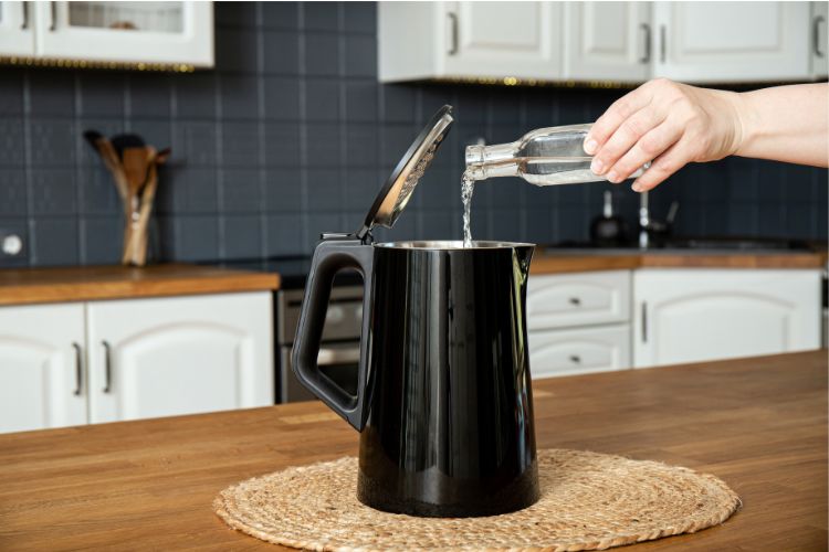 Woman pouring vinegar in kettle for descaling