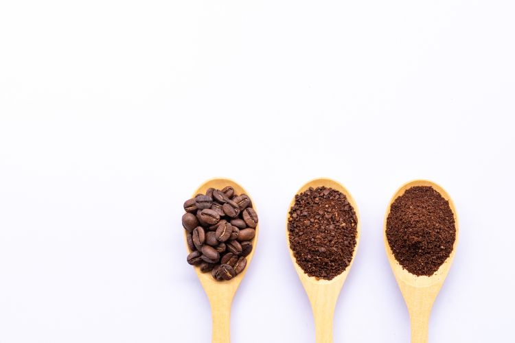 Wooden Spoons with Coffee Beans and Grounds on White Background